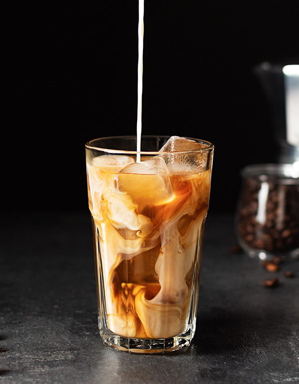 Pouring,Milk,Into,A,Glass,With,Iced,Coffee,Over,Black